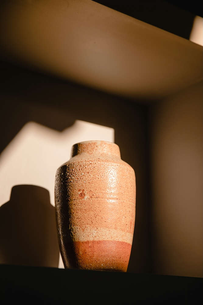 Soft-lit photo of an urn on a wooden table with a candle and framed family photo